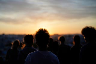 People watch the sunset in Lisbon